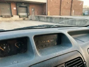 Verweerd dashboard van een gebruikte Maxus bestelbus met zichtbare kilometerstand, gefotografeerd op een industrieel laadperron.